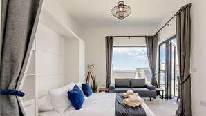 A bedroom with a bed, a sofa, a desk, and a view of the sky. - 6 Bed in Bideford (oc-91693) (Westward Ho!)