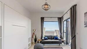 A modern living room with a sofa, ottomans, a tripod lamp, and a view of the sea. - 6 Bed in Bideford (oc-91693) (Westward Ho!)