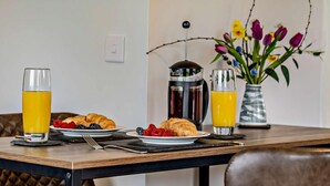 A breakfast setting with croissants, fruit, and two glasses of orange juice on a wooden table. - 1 Bed in Ventnor (oc-91536) (Godshill)