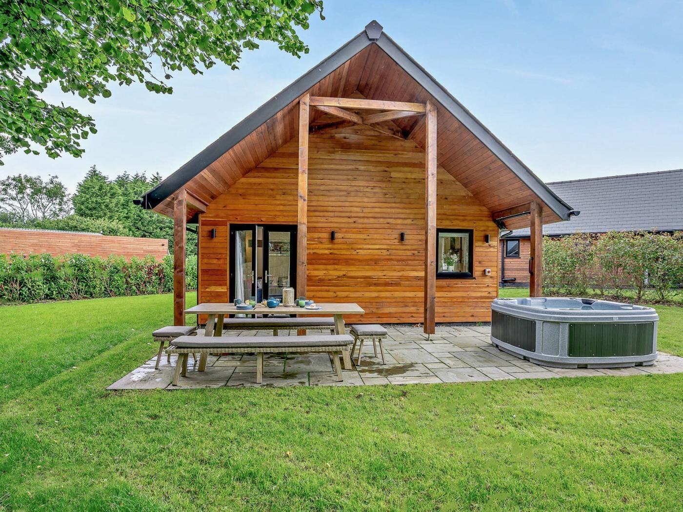 Une cabane en bois dotée d’une terrasse, d’un bain à remous et d’un coin repas.