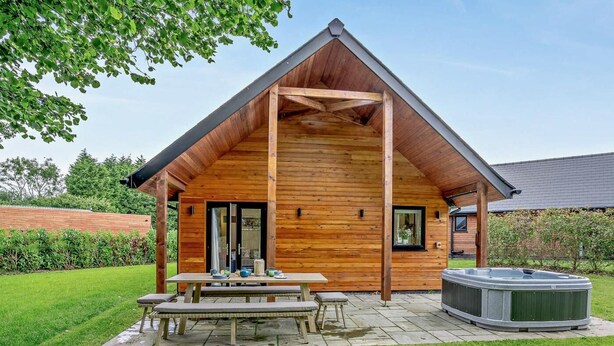 Eine Holz-Blockhütte mit Terrasse, Whirlpool und Essbereich.