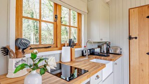 Una cocina con armarios de madera, un fregadero, una estufa y un ventanal con vistas a árboles.