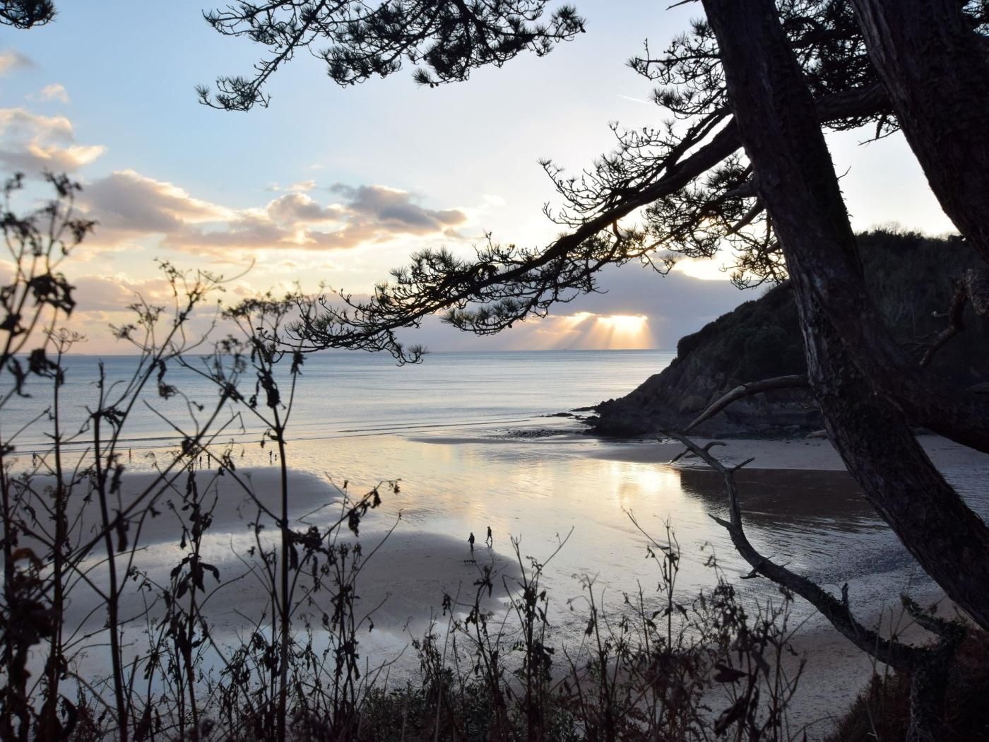 Un paisaje costero con mar tranquilo, acantilados rocosos y vegetación escasa.
