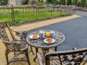 A round outdoor table with chairs, a breakfast setting with croissants and orange juice, and a garden view. - 2 Bed in Gloucester (oc-91603) (Upton Saint Leonards)