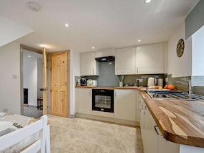 A modern kitchen with white cabinetry, a wooden countertop, and a built-in dishwasher. - 2 Bed in Gloucester (oc-91603) (Upton Saint Leonards)