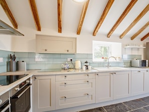 A modern kitchen with a central island, built-in oven, and a window providing natural light. - 6 Bed in Harlech (oc-91546) (Harlech)