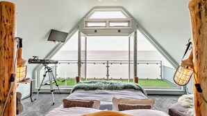 A bedroom with a large bed, a telescope, and a balcony with a view of the sea. - 3 Bed in Whitstable (oc-91641) (Seasalter)