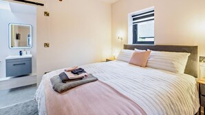 Quarto com cama, mesas de cabeceira, janela, espelho e luminária pendente.