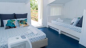 A room with two beds, a ceiling fan, and a view of the outdoors.