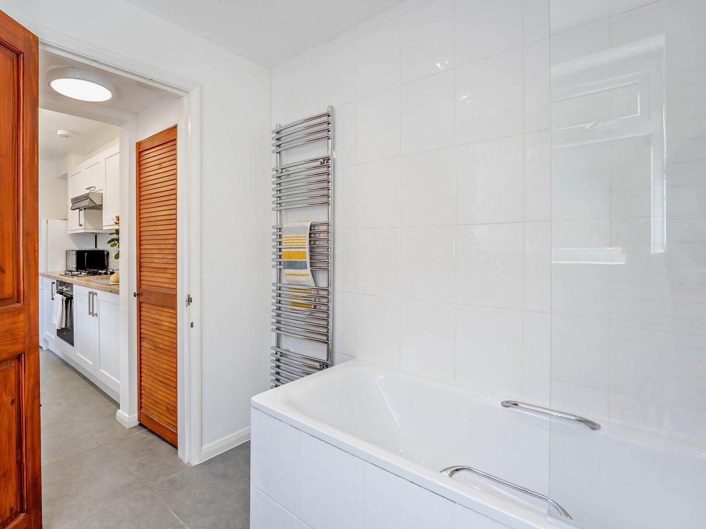 A modern bathroom with a white bathtub and a towel rack.