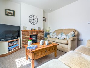 Ein Wohnzimmer mit Fernseher, Kamin, Sofa und Couchtisch.