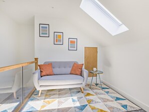 A modern living room with a grey sofa, a patterned rug, and framed artwork on the wall. - 4 Bed in Bideford (oc-91648) (Appledore)