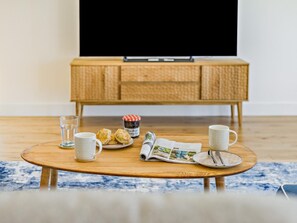A cozy living room with a wooden coffee table, a television on a stand, and a wicker cabinet. - 4 Bed in Bideford (oc-91648) (Appledore)