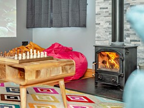 A cozy room with a chessboard, a pink bean bag, and a wood-burning stove.