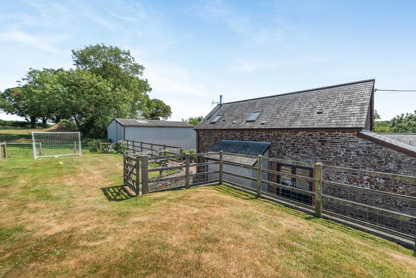 A rural property with a stone building, a fenced area, and a goalpost.