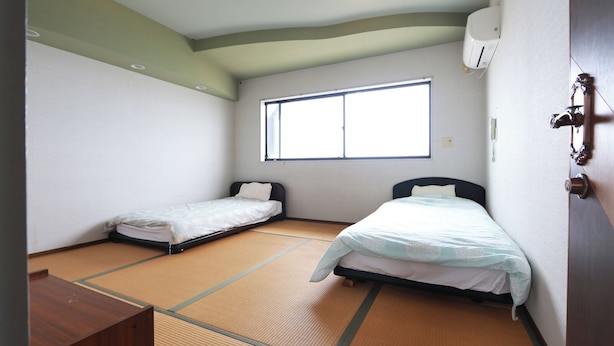 A room with two beds, tatami flooring, a window, and a door with a lock. - Del Mare Kiami (Masuda)