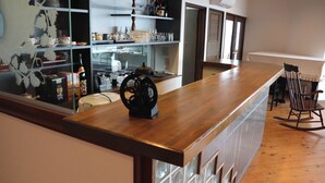 A bar area with a wooden counter, a vintage coffee grinder, and shelves with various items. - Del Mare Kiami (Masuda)