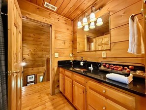 A wooden cabin interior with a kitchen area featuring a sink, cabinets, and a countertop with a towel and some food items. - Boulder Lodge - The Perfect Mountain Escape in Banner Elk near Winery & Hiking (Banner Elk)