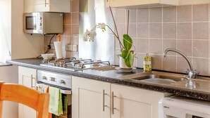 Een keuken met een magnetron, fornuis, spoelbak en een afwassysteem.