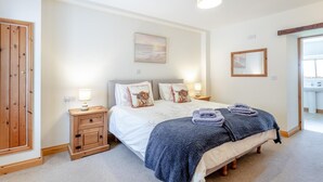Een slaapkamer met een bed, nachtkastjes, een spiegel en een raam.