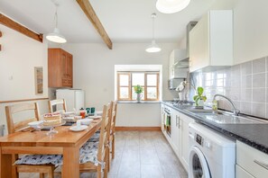 Une cuisine moderne avec un coin repas, des chaises en bois, une table dressée et un lave-linge.