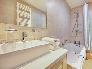Un baño con un lavamanos grande, una bañera, una ducha y un perchero para toallas.