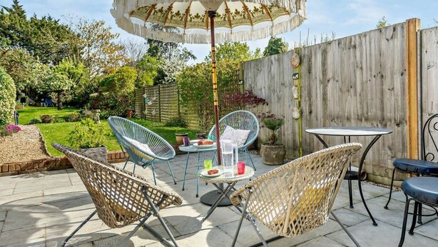 A patio with wicker chairs, a table, and an umbrella. - 2 Bed in Poole (oc-91757) (Poole)