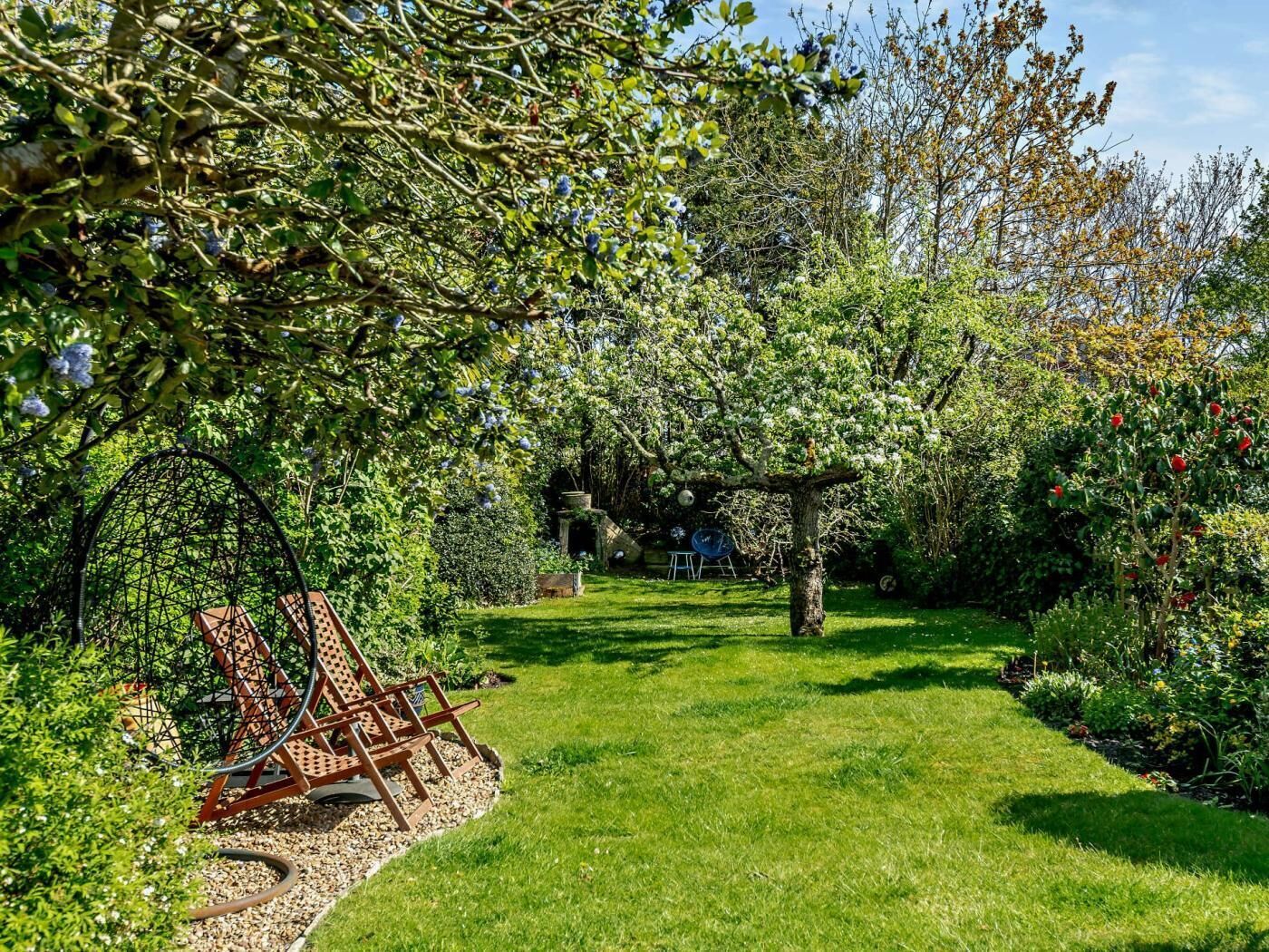 Un jardin avec une pelouse, une balançoire et un arbre en fleurs.