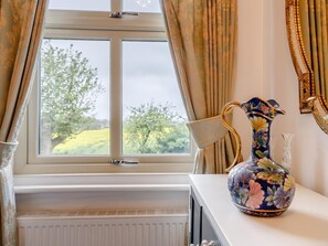 Ein Zimmer mit Fenster, Heizkörper und einer Vase auf einem Tisch.