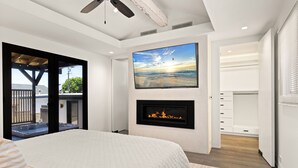 Ein Schlafzimmer mit einem Bett, einem Kamin, einem Fernseher und einem Balkon.