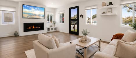 Una sala de estar moderna con chimenea, asientos cómodos y un televisor grande.