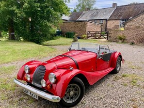 A vintage red convertible car parked on a gravel driveway. - 1 Bed in Chepstow (oc-91941) (Chepstow)