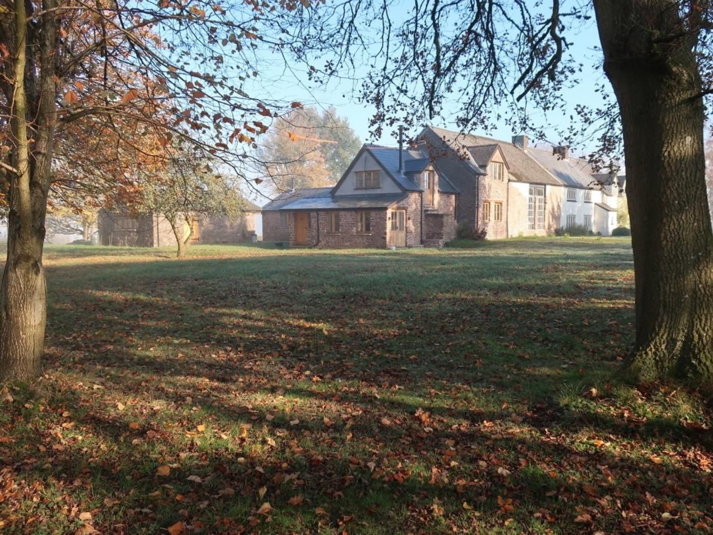 A large house with a spacious lawn, surrounded by trees with autumn leaves.