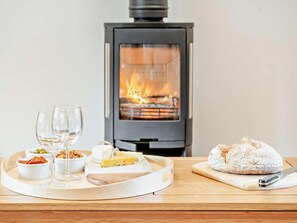 A cozy room with a wood-burning stove, a tray with food and drinks, and a loaf of bread on a cutting board. - 1 Bed in Chepstow (oc-91941) (Chepstow)