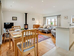 A living room with a fireplace, a dining area with a table and chairs, and a kitchen area with a countertop and cabinets. - 1 Bed in Chepstow (oc-91941) (Chepstow)