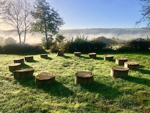 Ein grasbewachsenes Feld mit mehreren in einem Kreis angeordneten Holzstümpfen.