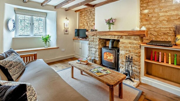 A cozy living room with exposed wooden beams, a stone fireplace, a television, and a bookshelf. - 2 Bed in Banbury (oc-92008) (Hook Norton)