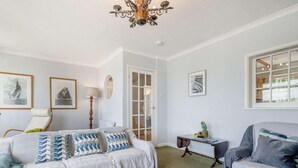 A living room with a sofa, armchair, rug, and a chandelier. - 2 Bed in Fowey (oc-92080) (Fowey)