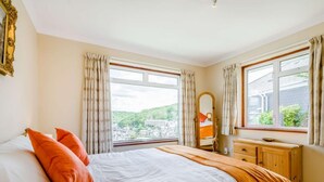 A bedroom with a bed, a dresser, a mirror, and large windows with curtains. - 2 Bed in Fowey (oc-92080) (Fowey)