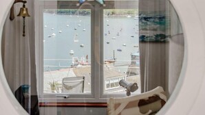 A room with a circular window overlooking a marina with boats. - 2 Bed in Fowey (oc-92080) (Fowey)