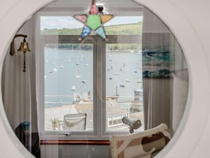 Ein Zimmer mit rundem Fenster, das auf einen Yachthafen mit Booten blickt.