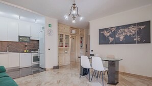 A modern kitchen with white cabinets, a built-in oven, and a dining area with a glass table and white chairs. - 2-bedroom apartment • St. Paul's Basilica • Metro B, 600 meters • A/C (Roma)