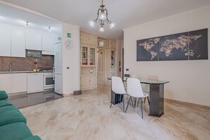A modern kitchen with white cabinets, a built-in oven, and a dining area with a glass table and white chairs. - 2-bedroom apartment • St. Paul's Basilica • Metro B, 600 meters • A/C (Roma)