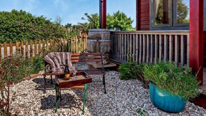 A wooden deck with a bench, a table with a bottle and glass, and a potted plant. - 1 Bed in Bristol (oc-91933) (Claverham)