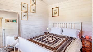 A bedroom with a white bed, a patterned rug, and framed artwork on the wall.