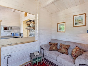 A cozy interior with a wooden ceiling, a sofa with patterned cushions, a small stool, and a framed picture on the wall. - 1 Bed in Bristol (oc-91933) (Claverham)