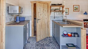 A compact kitchen with a microwave, kettle, and sink. A door leads to another room. - 1 Bed in Bristol (oc-91933) (Claverham)
