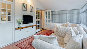 Un salon spacieux avec un grand canapé, un téléviseur fixé au mur et un tapis à motifs.
