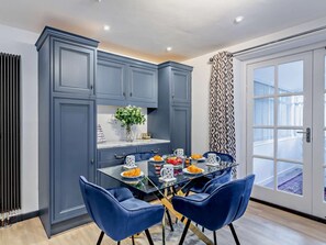 Une cuisine moderne avec des meubles de rangement bleus, une table à manger en verre et des chaises bleues.