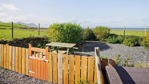 A wooden gate leading to a gravel path with a picnic table and benches. - 2 Bed in Caernarfon (oc-92082) (Aberdesach)